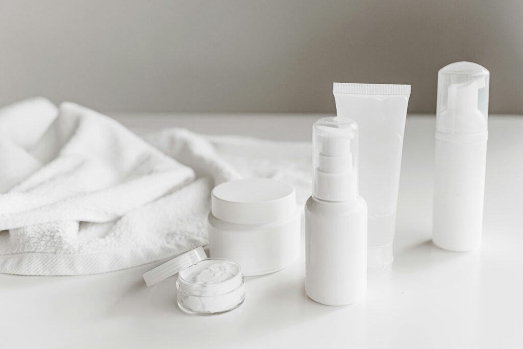 A simple layout of essential products for a skincare routine for beginners, including white bottles of cleanser and moisturizer.