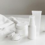 A simple layout of essential products for a skincare routine for beginners, including white bottles of cleanser and moisturizer.